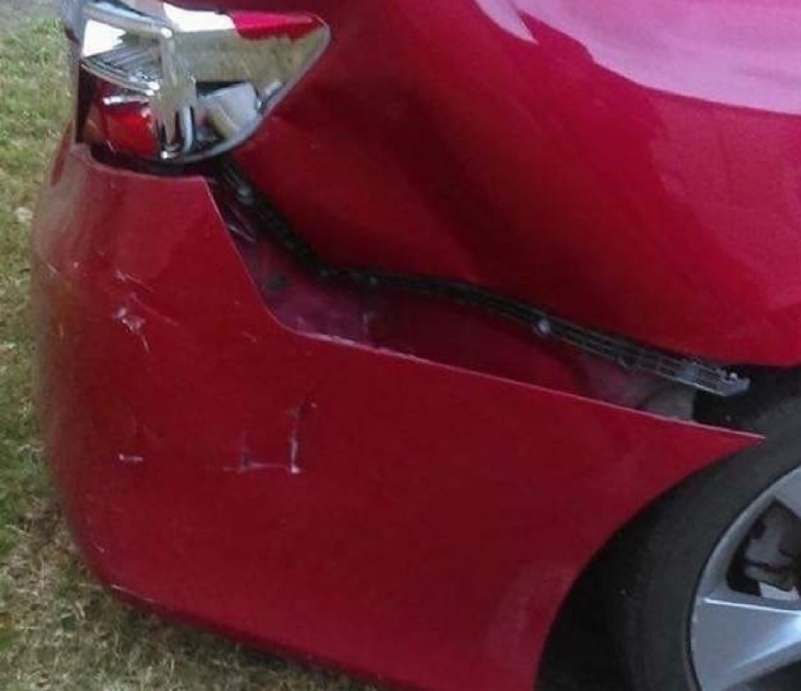 Red sedan with a crushed rear bumper and broken taillight before repair